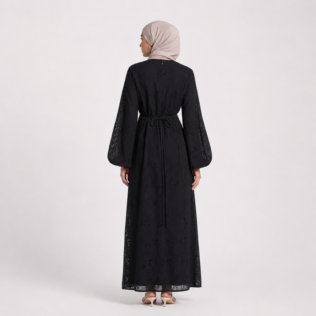 Woman wearing a black dress with lace details on a white background