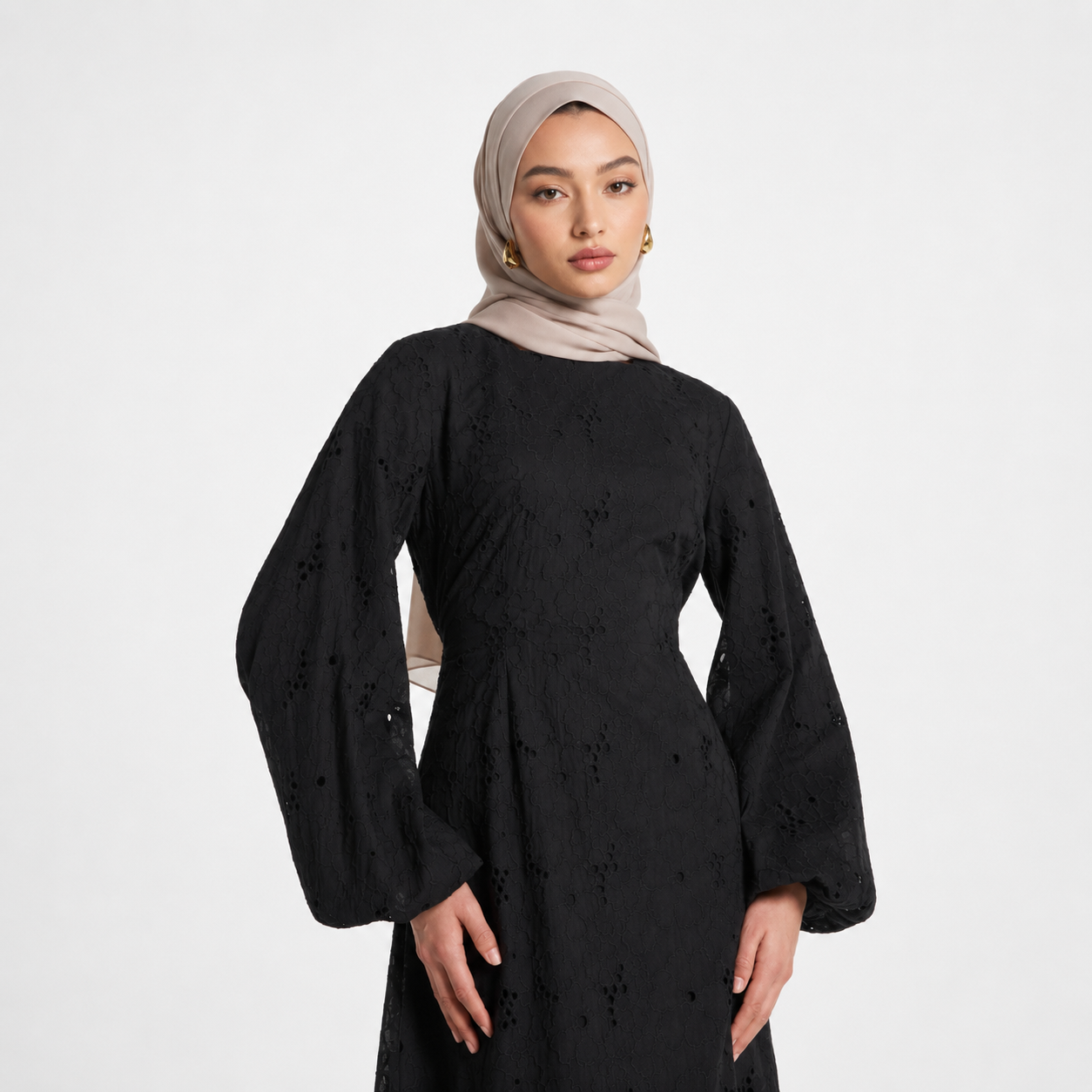 Woman wearing a black dress with intricate patterns on a white background