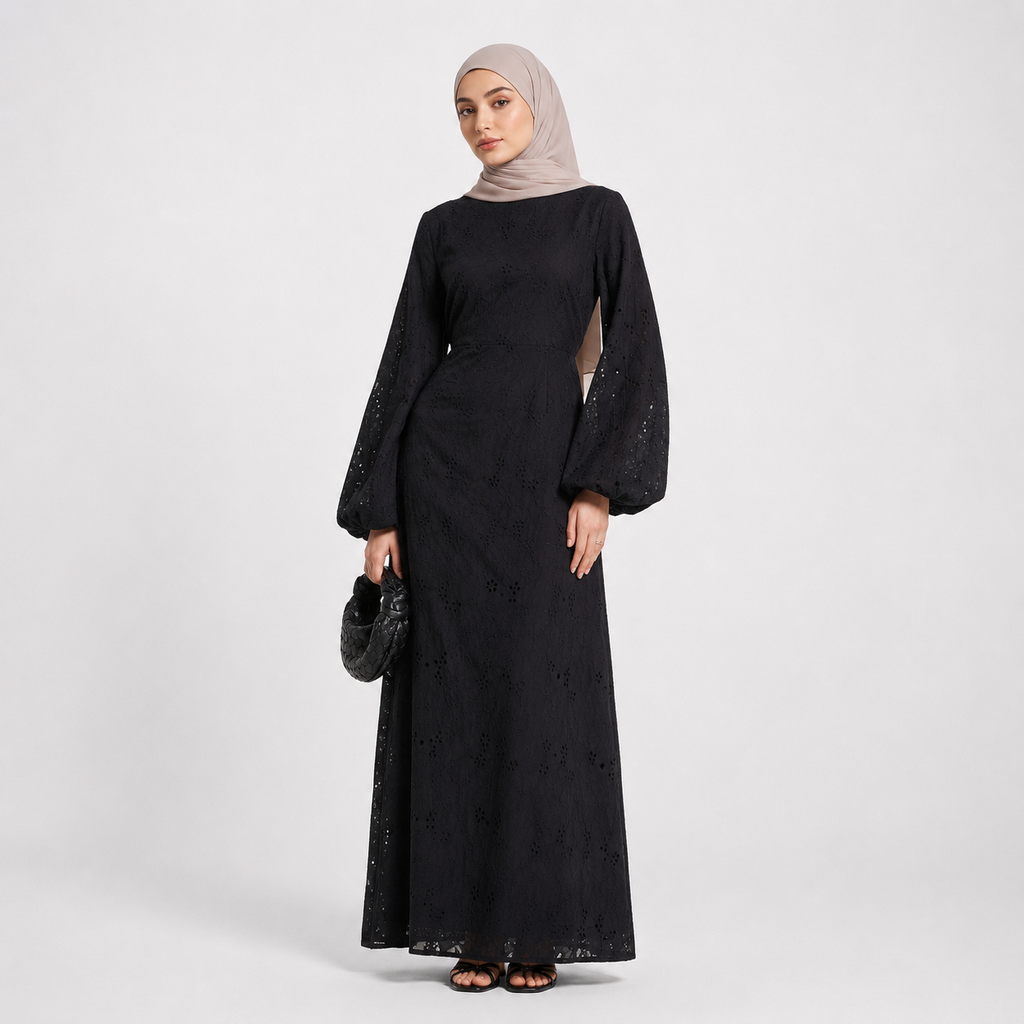 Woman wearing a black dress with long sleeves and a beige hijab on a white background