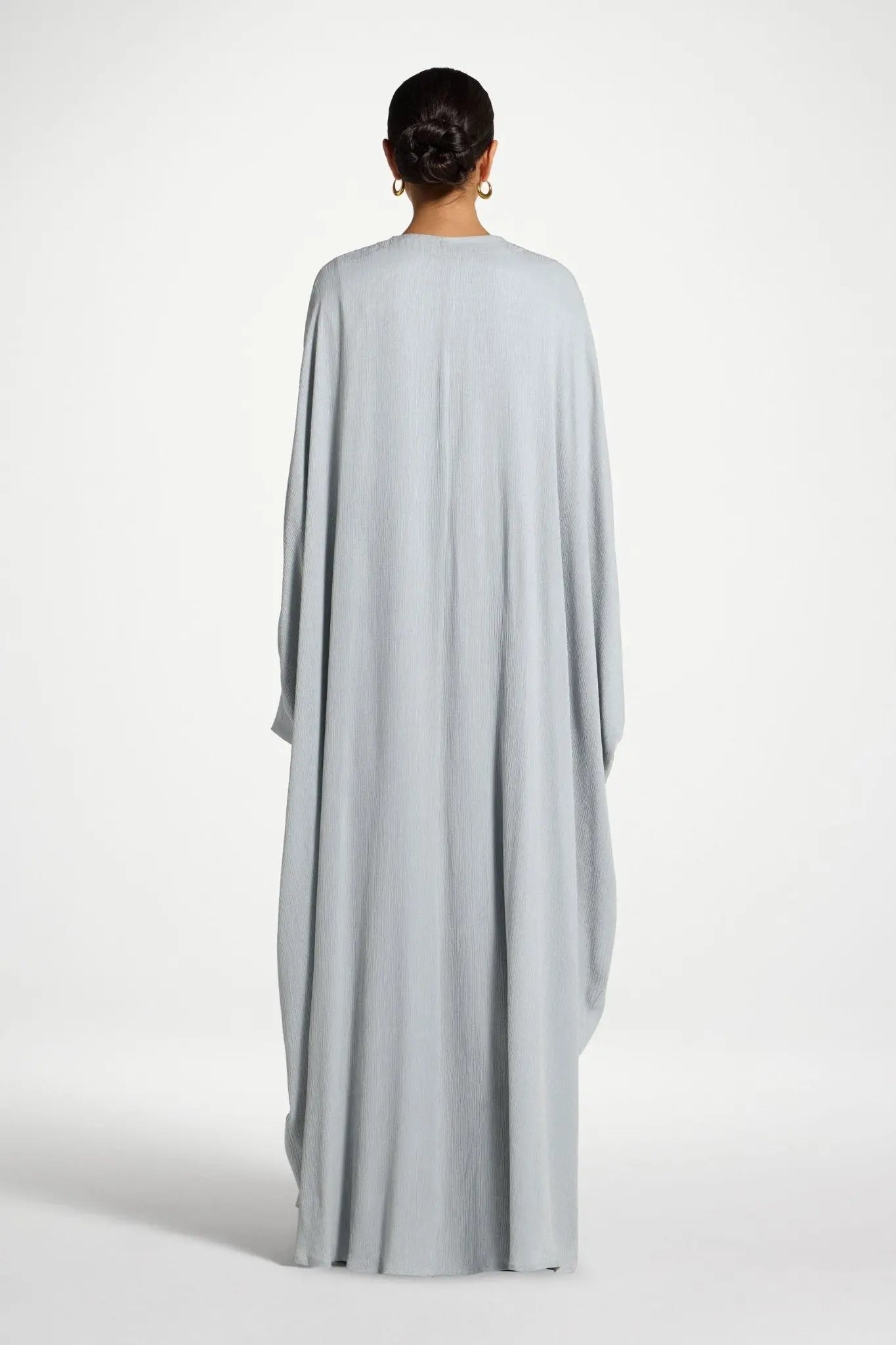 Person wearing a light gray long dress on a white background
