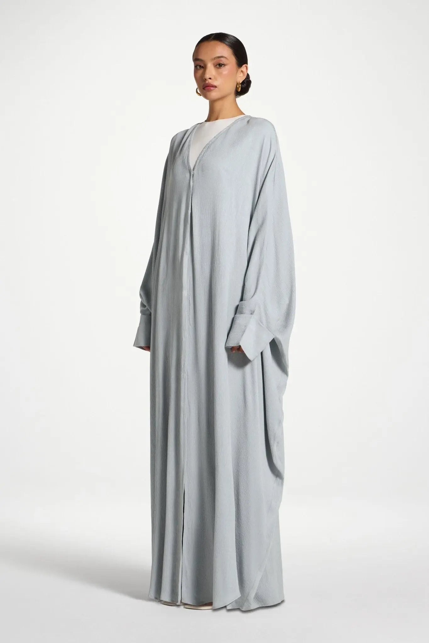 Woman wearing a light gray abaya on a white background