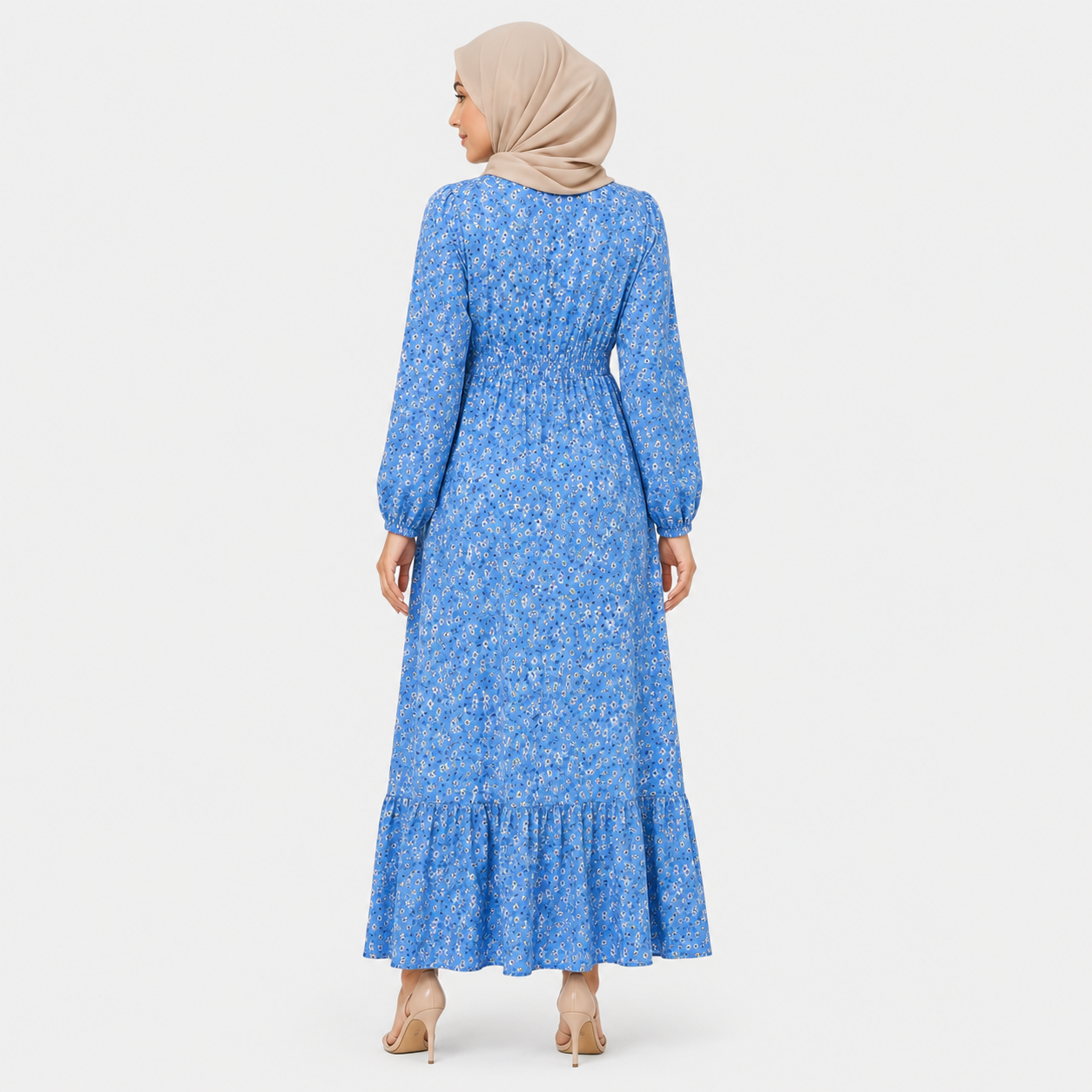 Woman wearing a blue floral dress with a beige hijab on a white background
