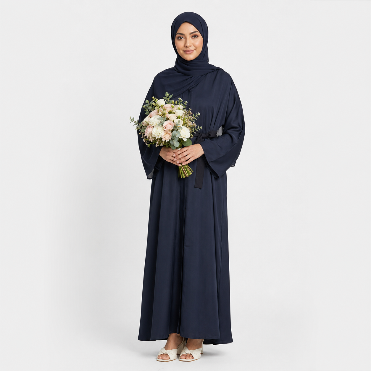 Woman in a navy abaya holding a bouquet of flowers on a white background
