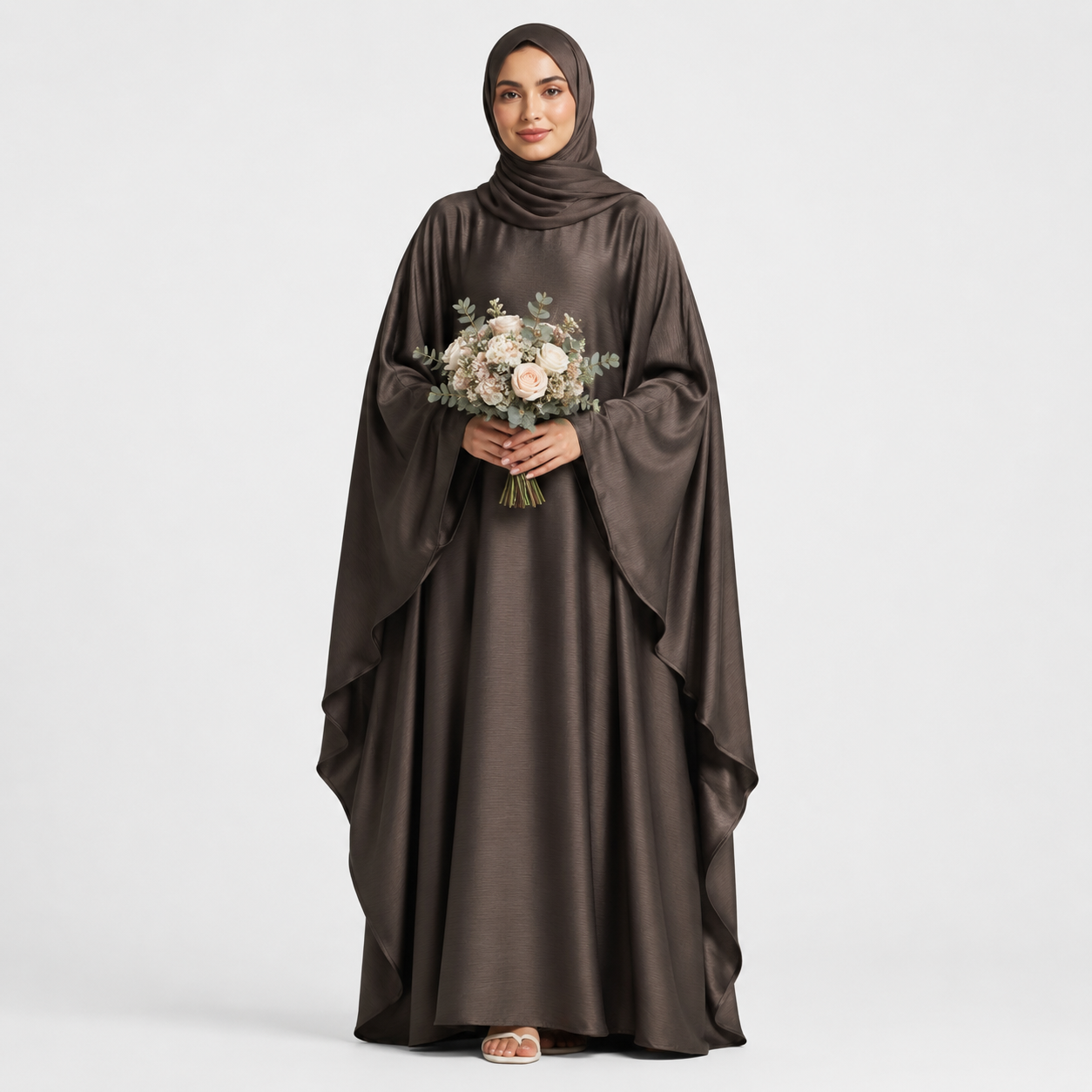 Woman wearing a brown abaya holding flowers on a white background