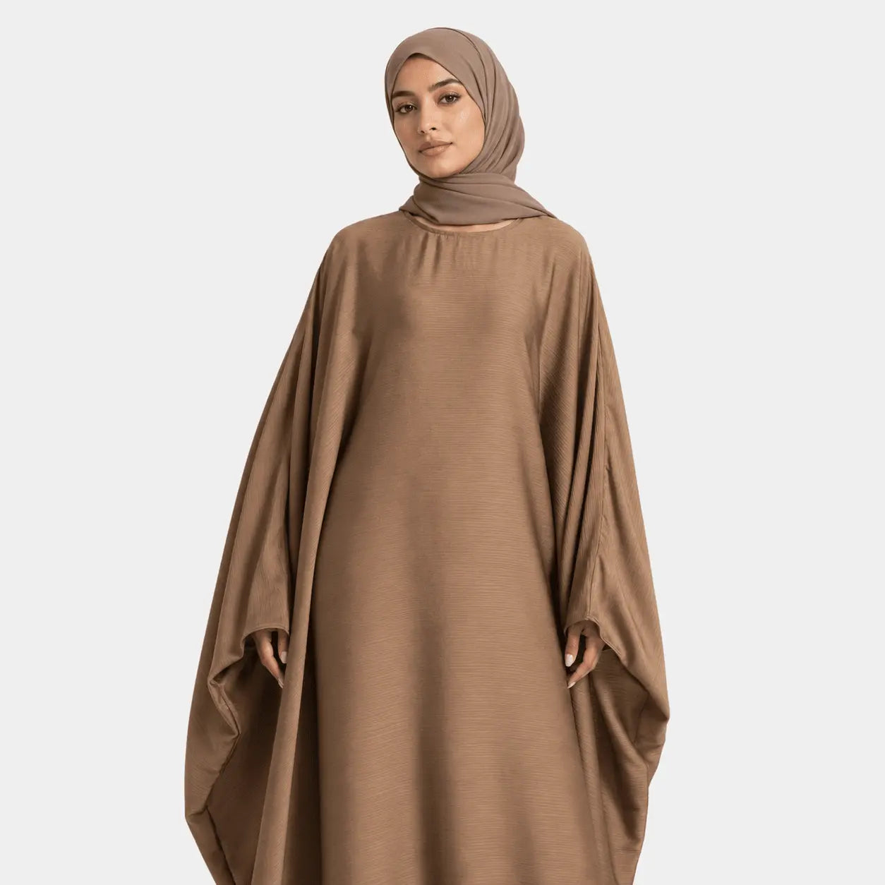 Woman wearing a brown abaya and hijab on a white background