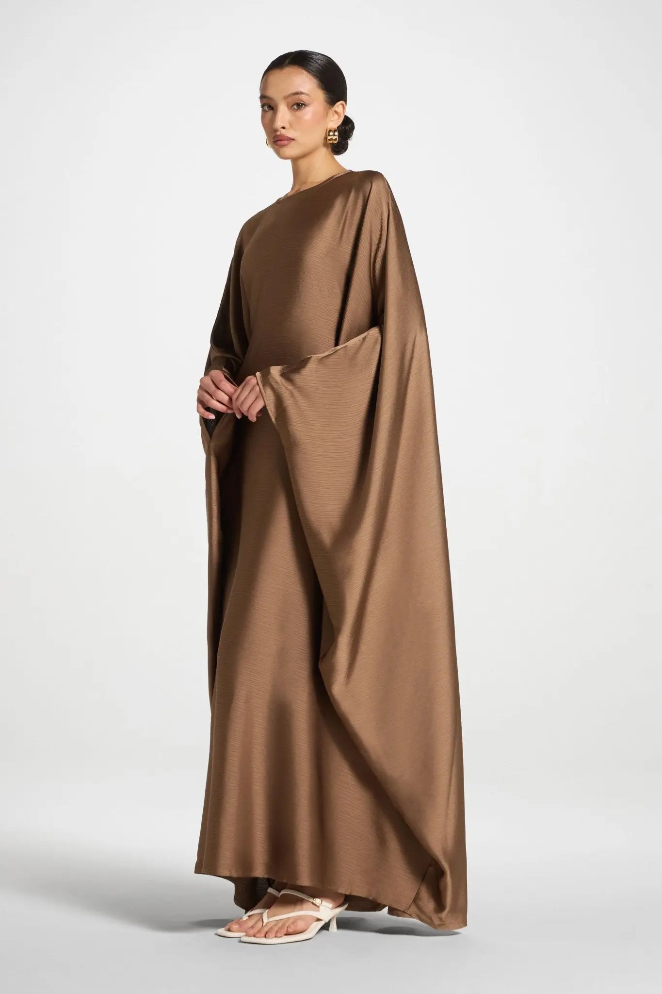 Woman wearing a brown cape over a plain background