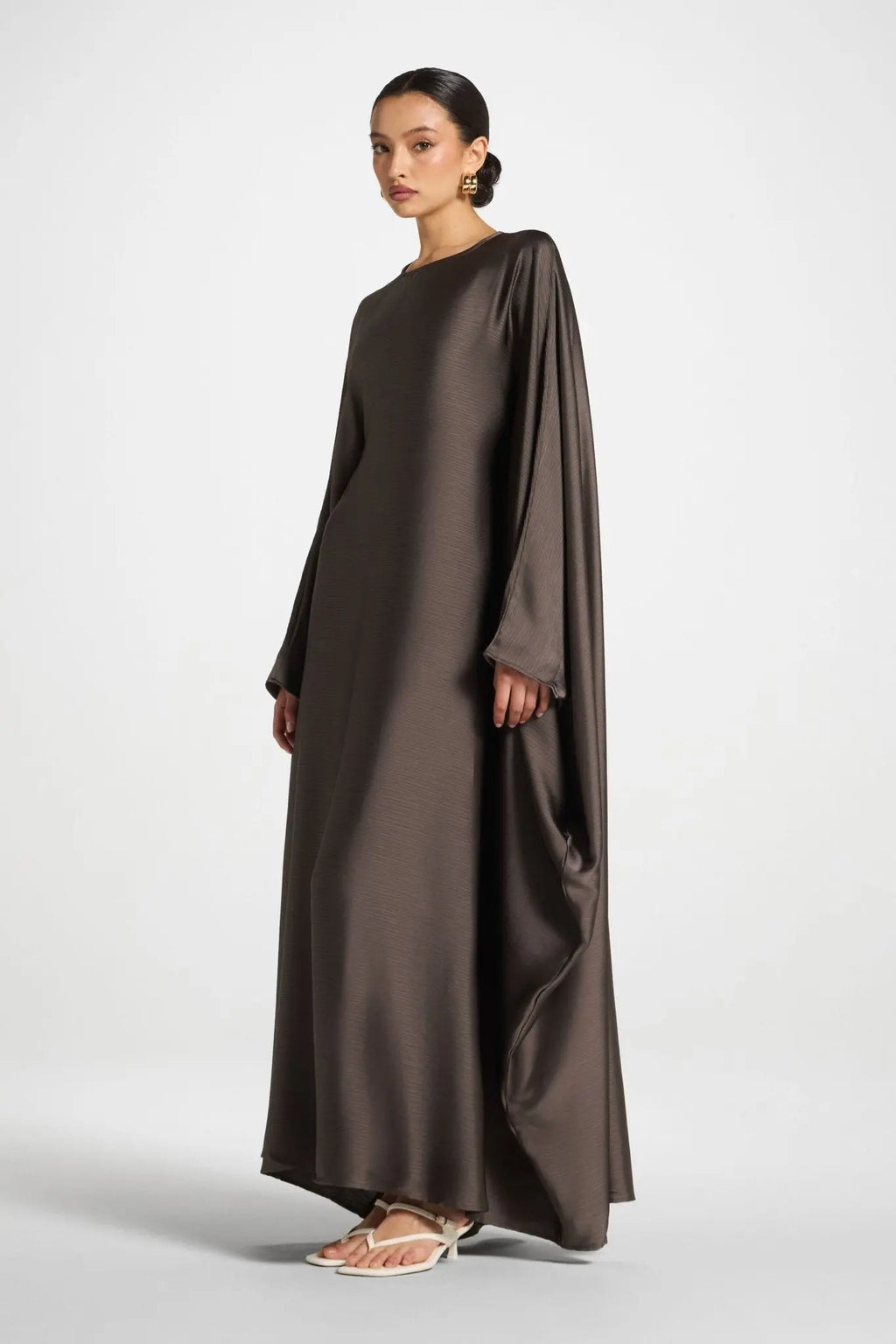 Woman wearing a long, dark brown dress on a white background