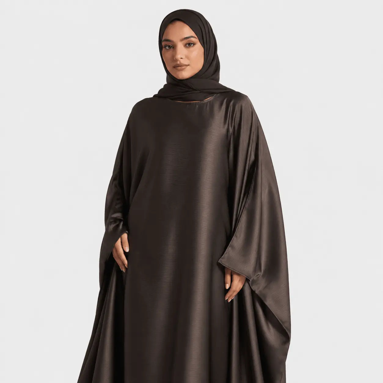 Woman wearing a dark brown abaya on a white background