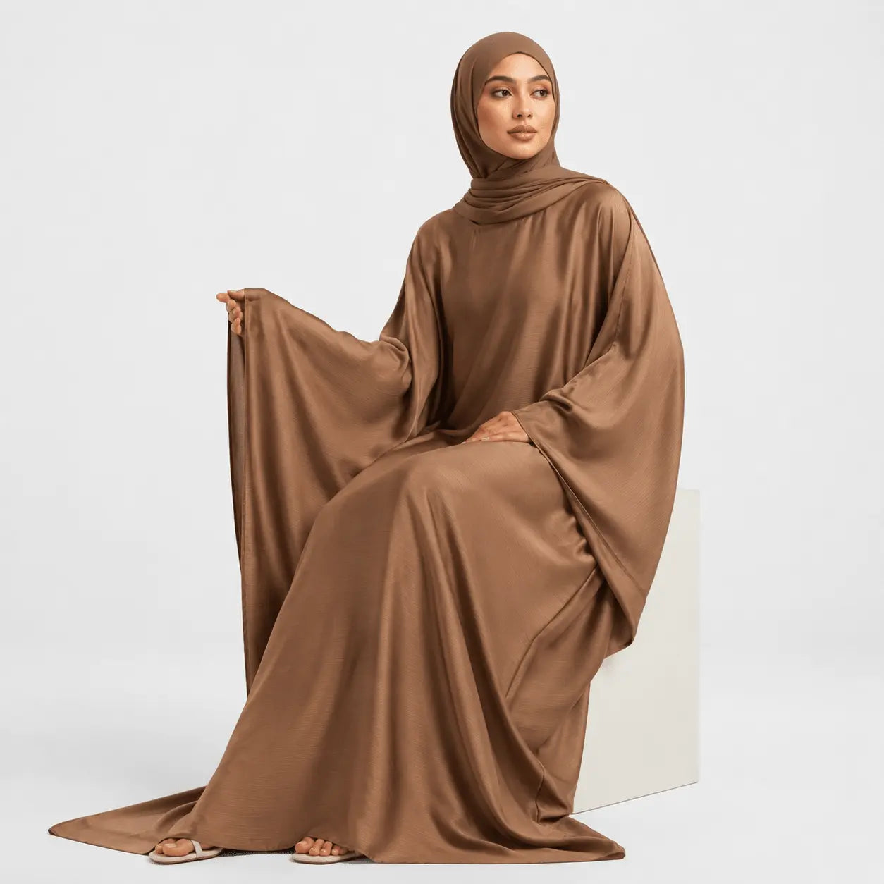 Woman wearing a brown abaya on a white background