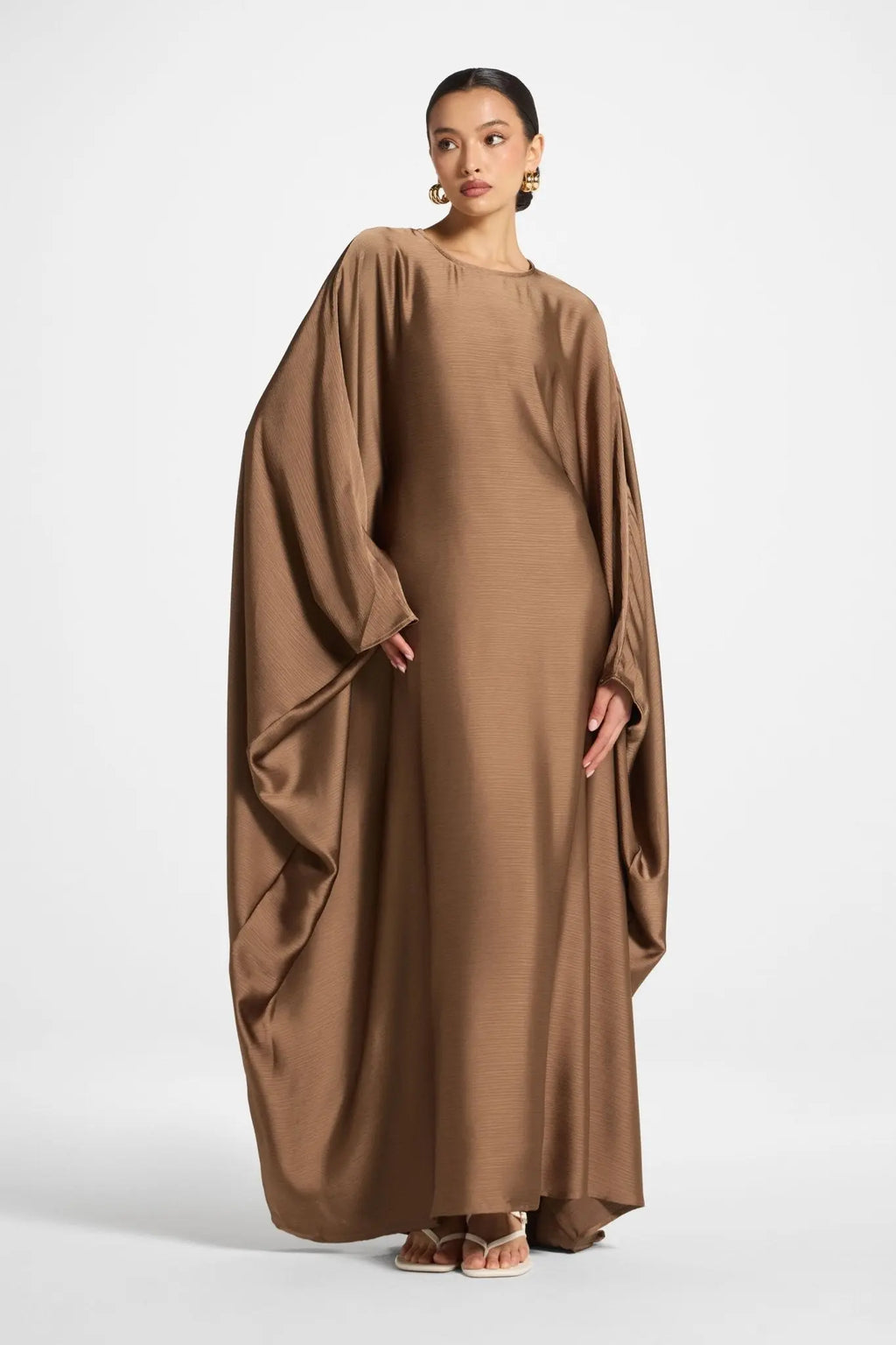 Woman wearing a brown flowing dress on a white background