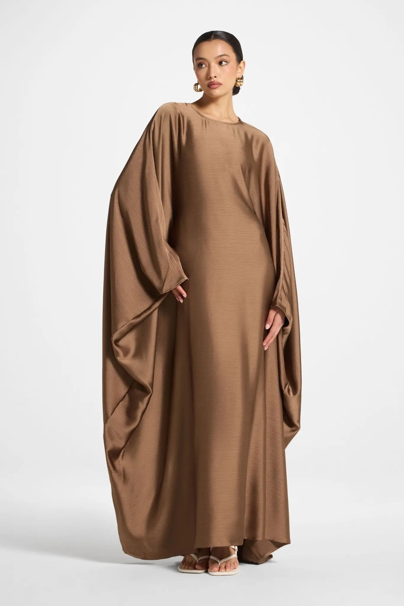 Woman wearing a brown flowing dress on a white background