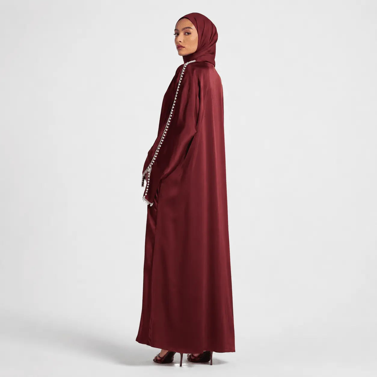 Maroon abaya with pearl details on a white background