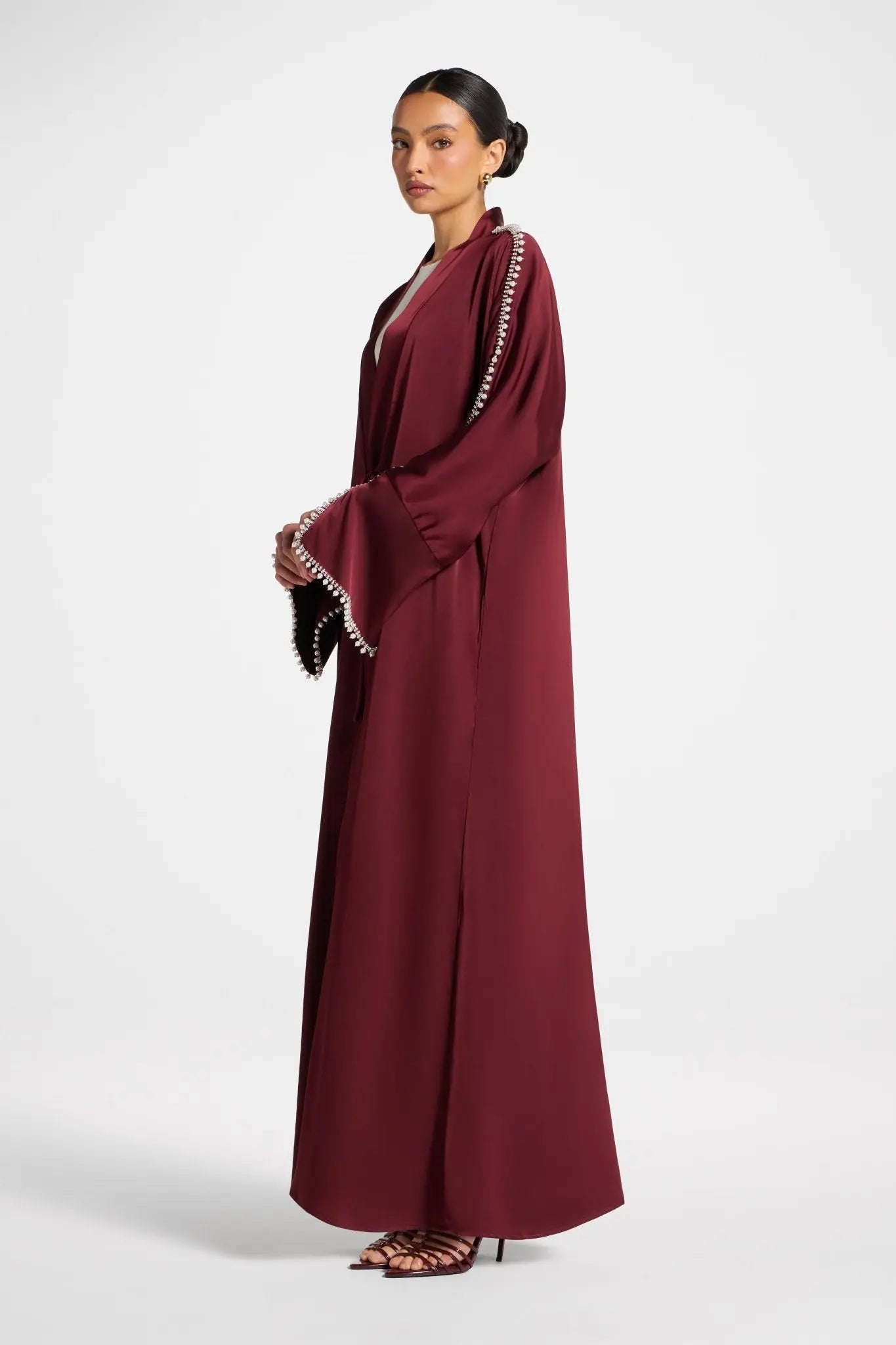 Woman wearing a burgundy dress with white embroidery on a white background