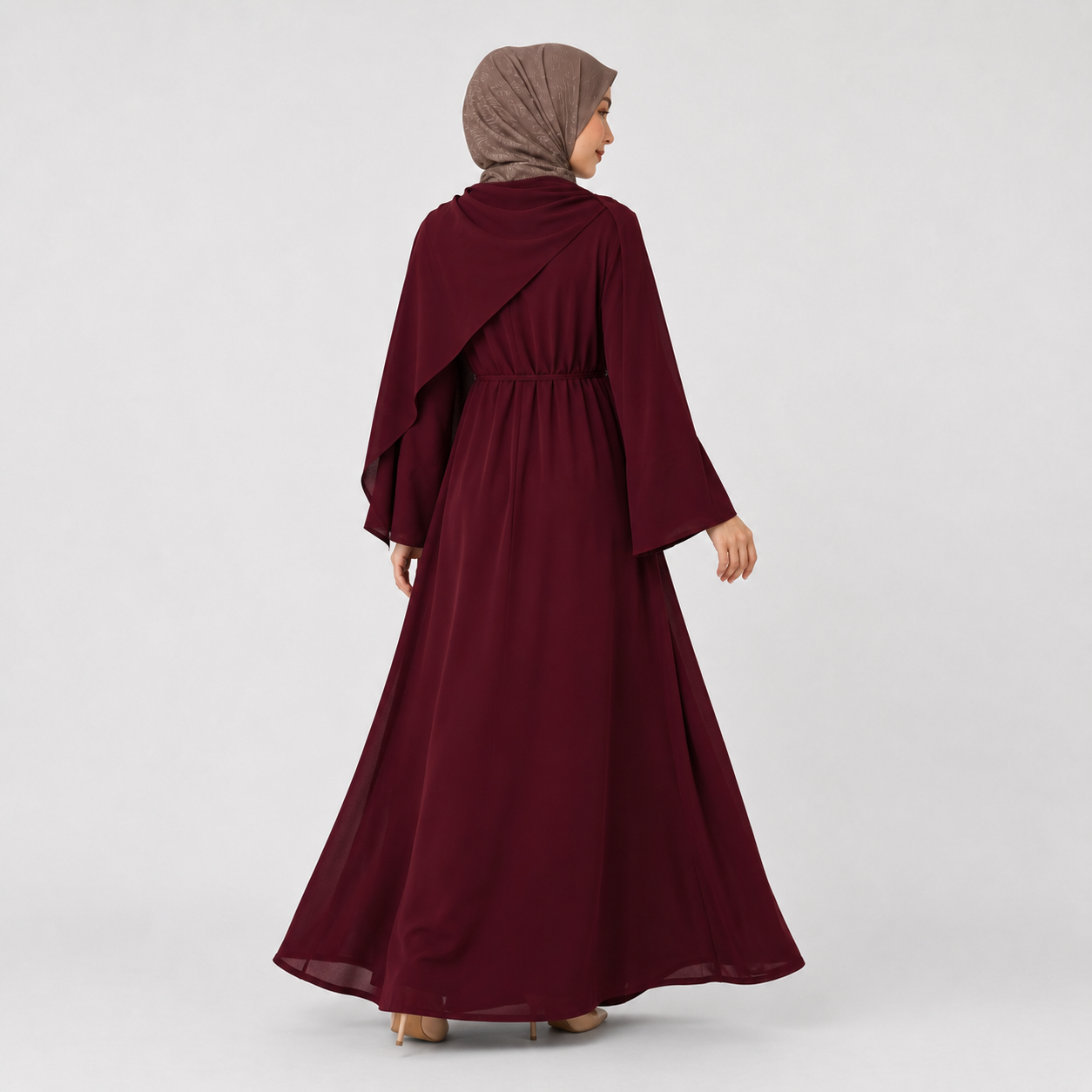 Woman wearing a burgundy abaya and headscarf on a white background