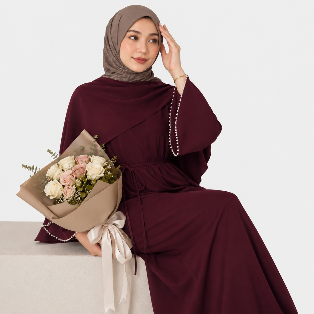 Woman in a burgundy dress holding a bouquet of flowers on a white background
