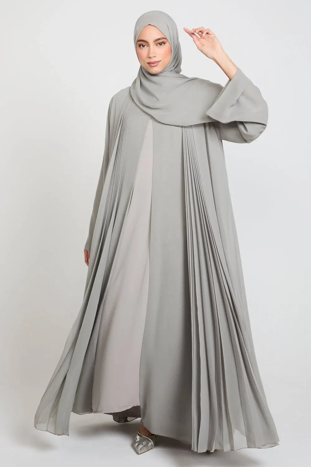 Woman wearing a gray abaya and hijab on a white background
