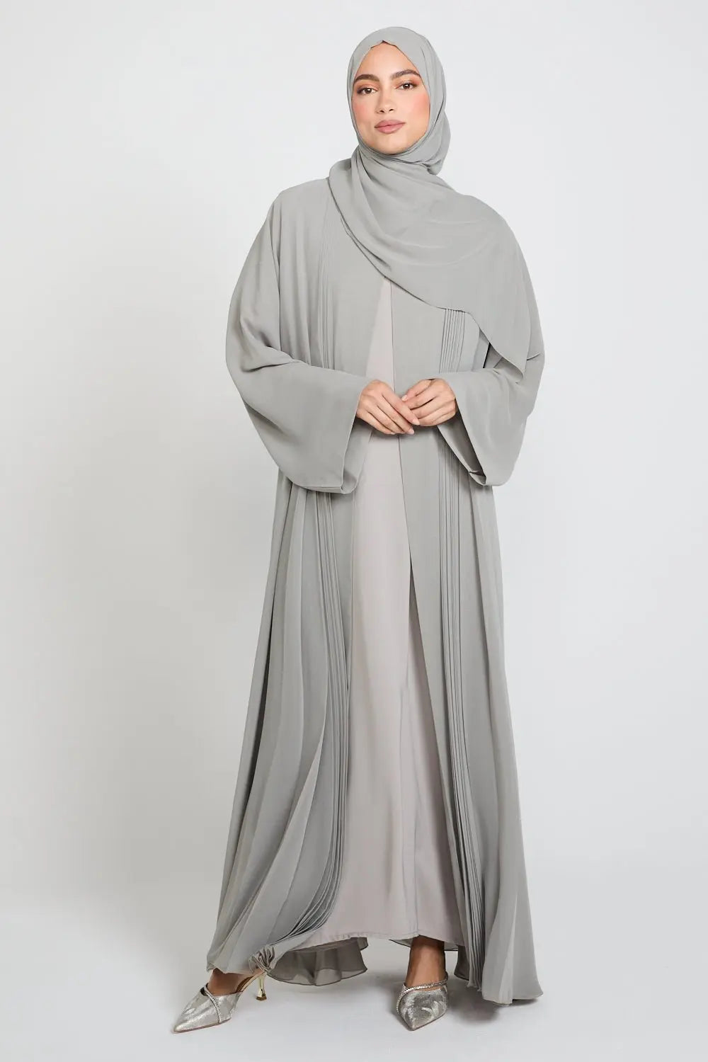 Woman wearing a gray abaya and hijab on a white background