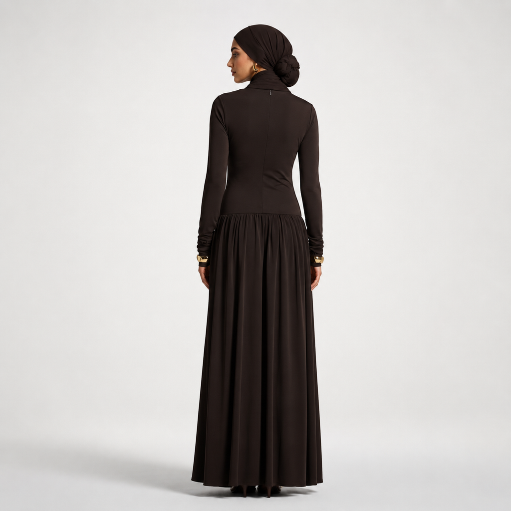 Woman wearing a long black dress with a plain background