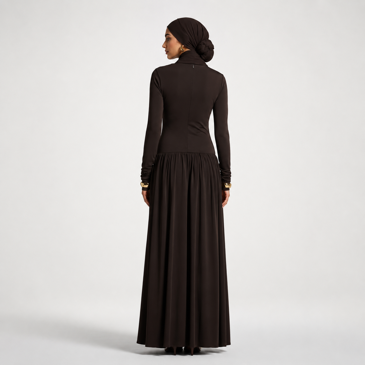 Woman wearing a long black dress with a plain background