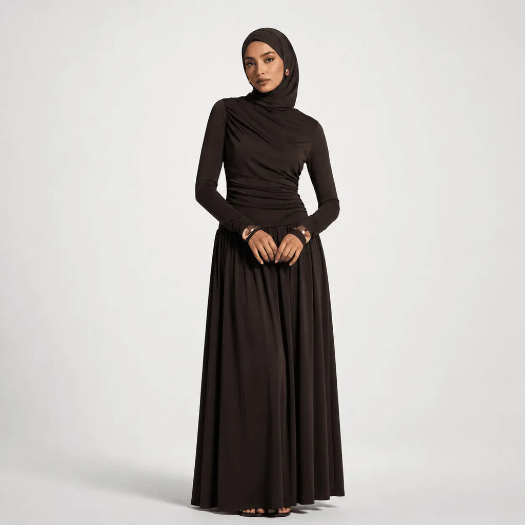 Woman wearing a long black dress with a hijab on a white background