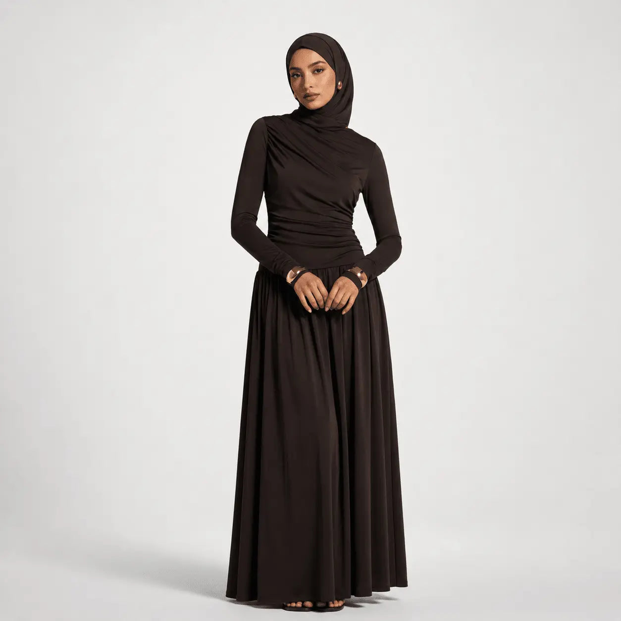 Woman wearing a long black dress with a hijab on a white background