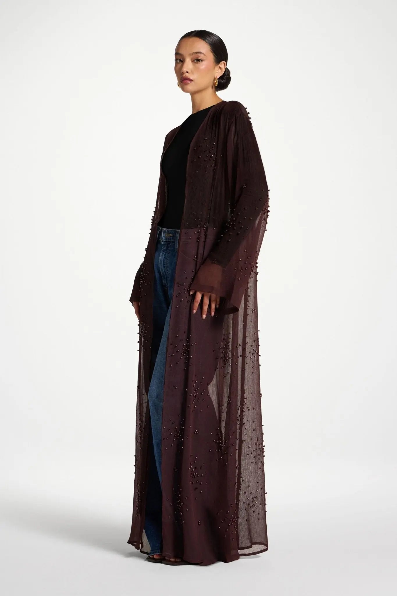 Woman wearing a long brown dress with a black top on a white background