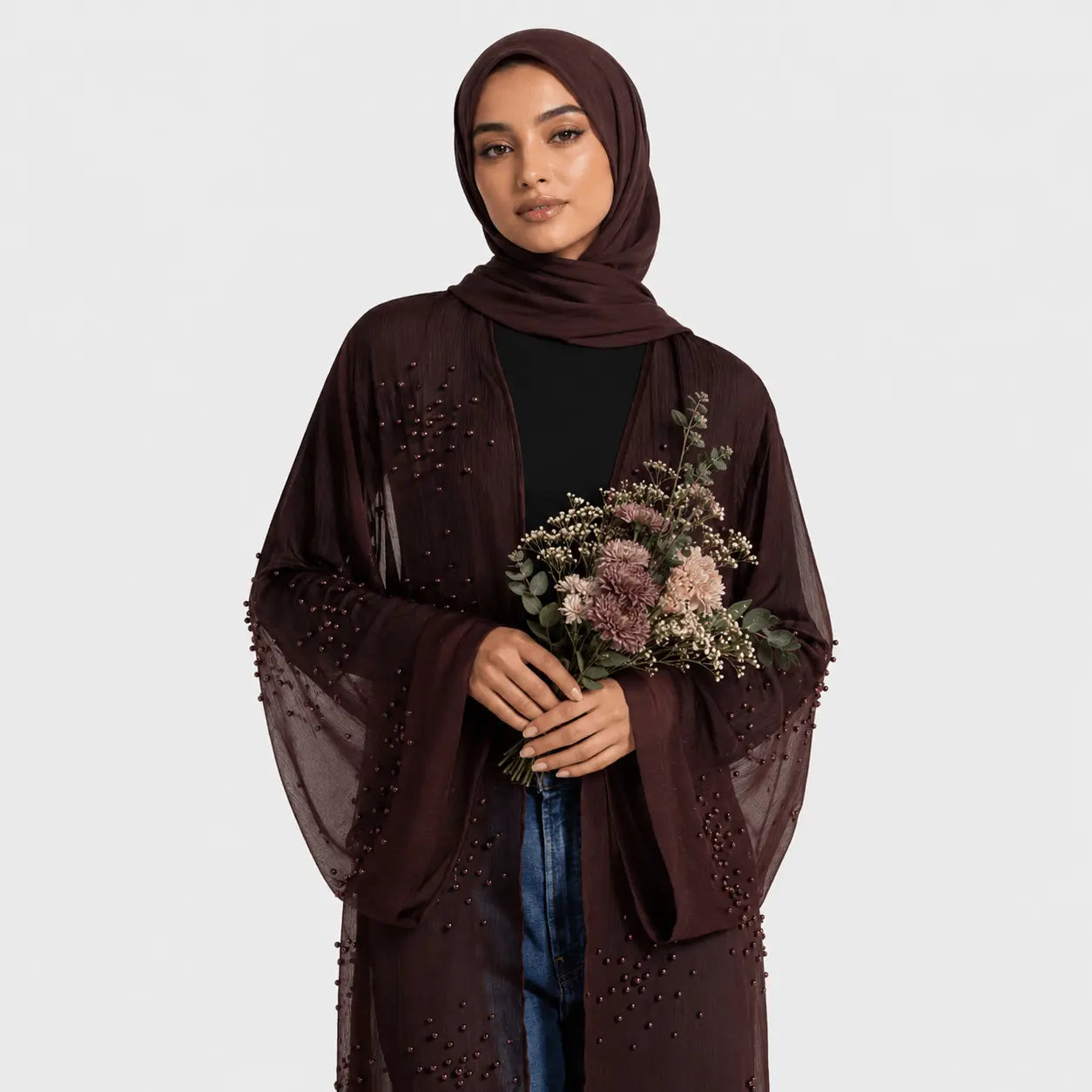 Woman wearing a brown hijab and holding flowers against a white background
