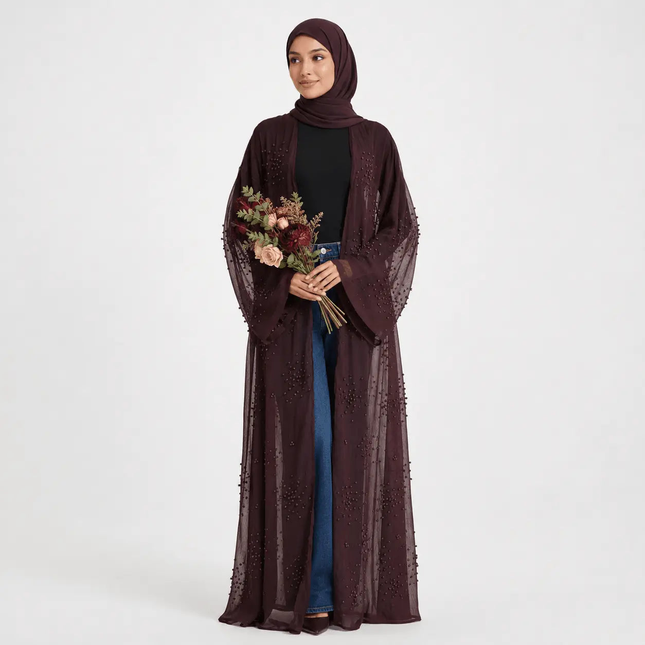 Woman wearing a dark brown abaya holding flowers on a white background