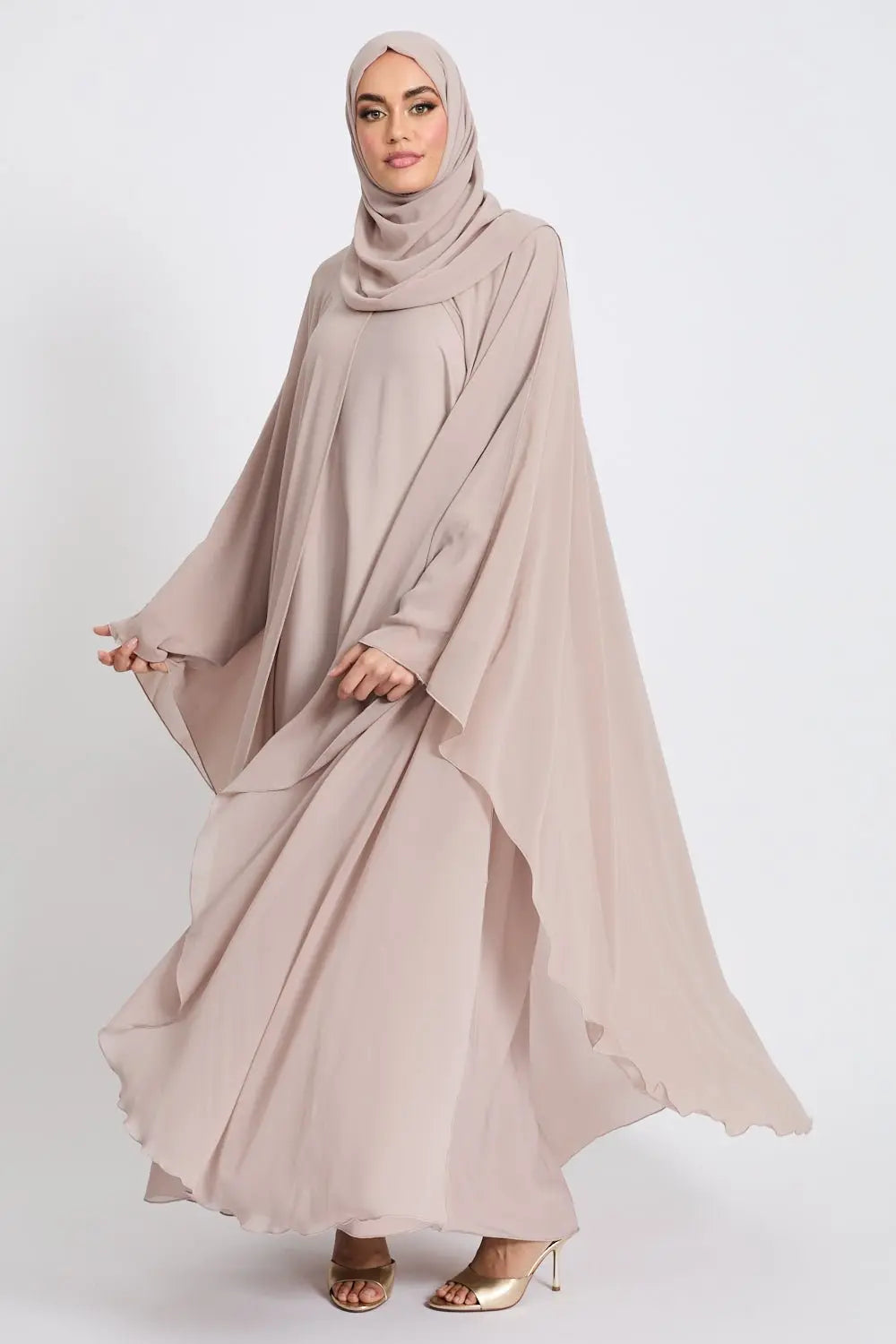Woman wearing a beige abaya and hijab on a white background
