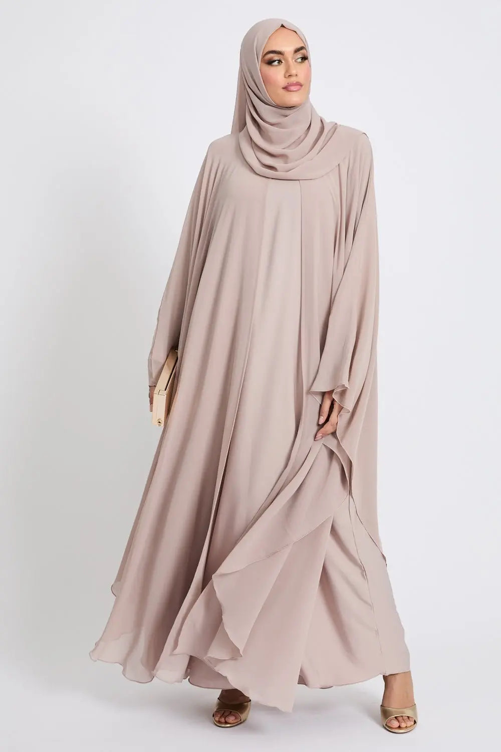 Woman wearing a beige hijab and abaya on a white background