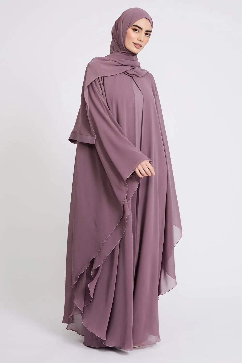 Woman wearing a mauve abaya and hijab on a white background
