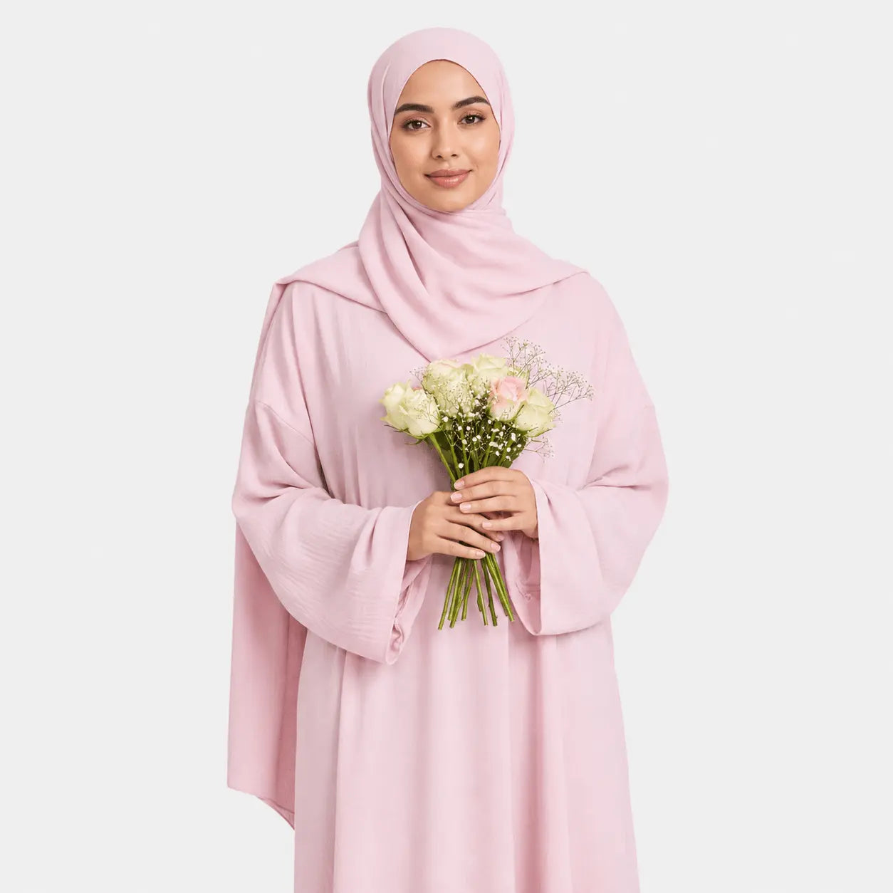 Woman wearing a pink hijab and holding flowers against a light gray background