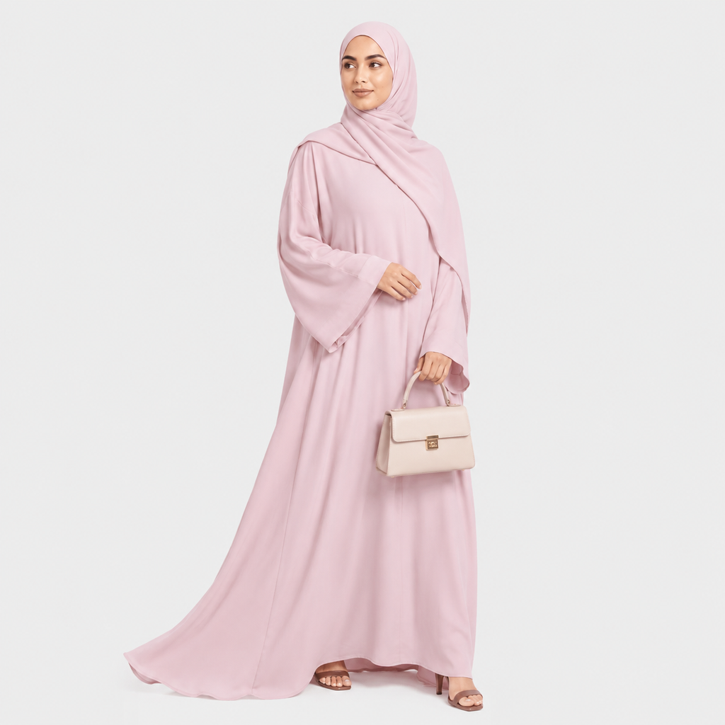 Woman wearing a pink abaya and hijab, holding a beige handbag on a white background