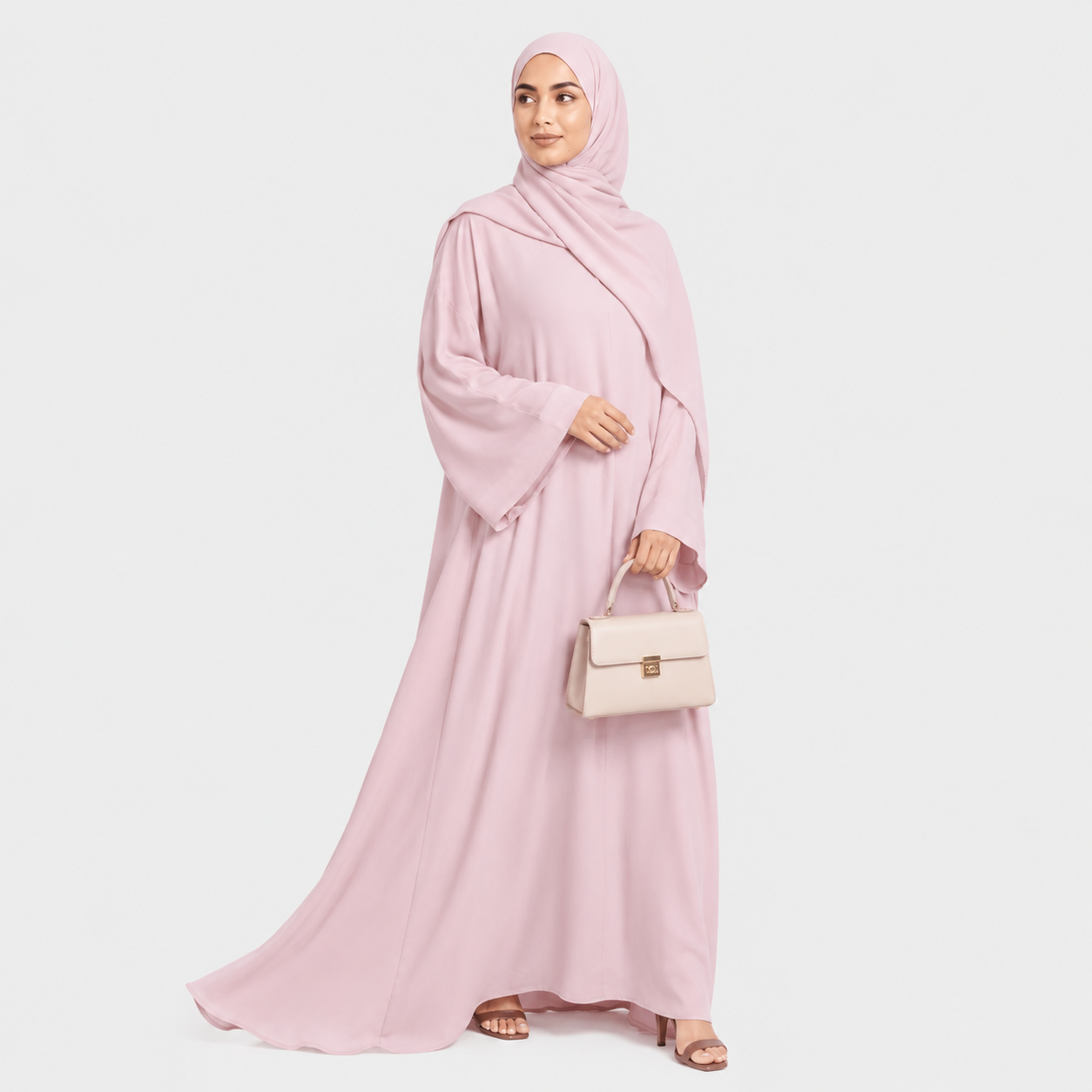 Woman wearing a pink abaya and hijab, holding a beige handbag on a white background