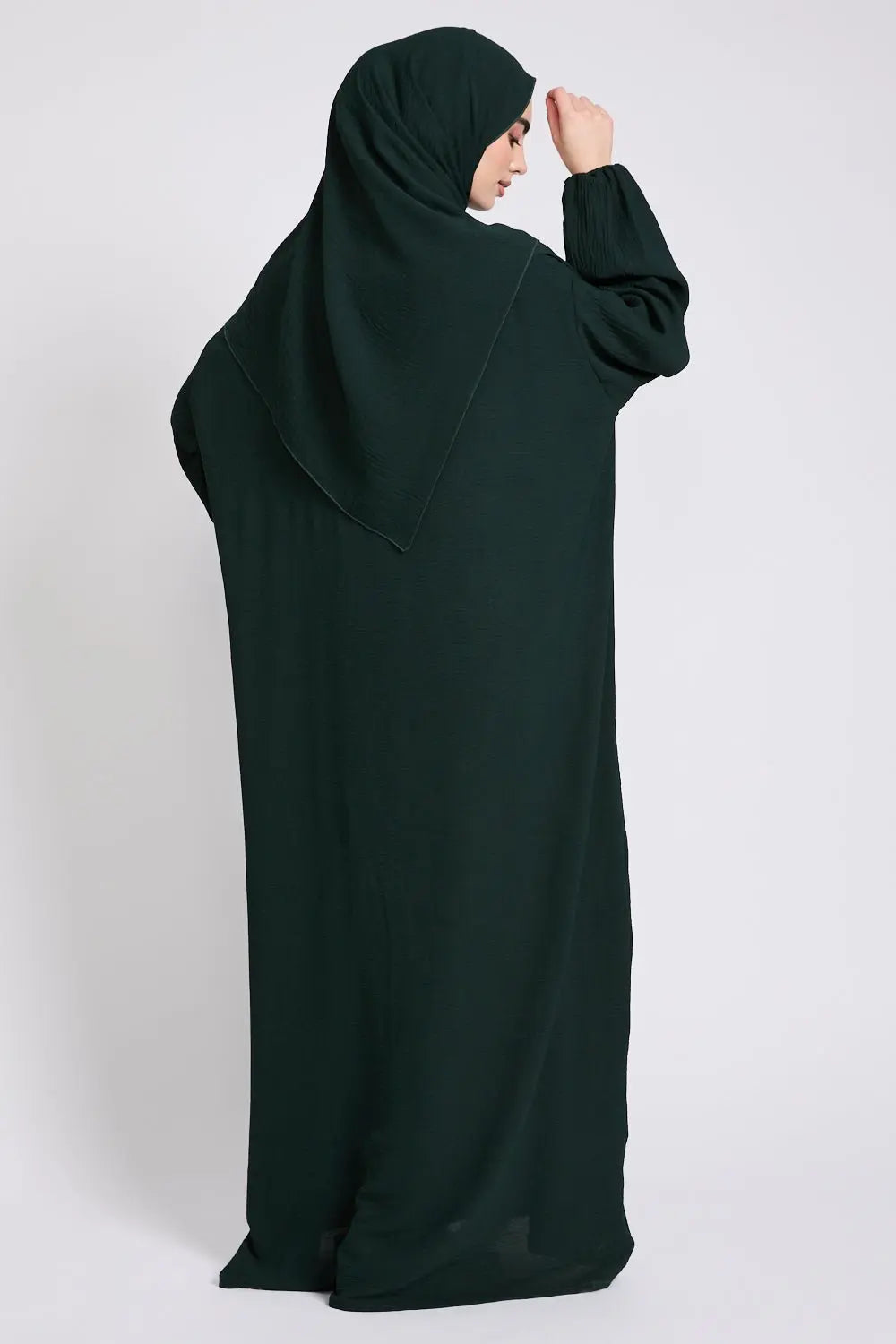 Person wearing a dark green abaya on a white background