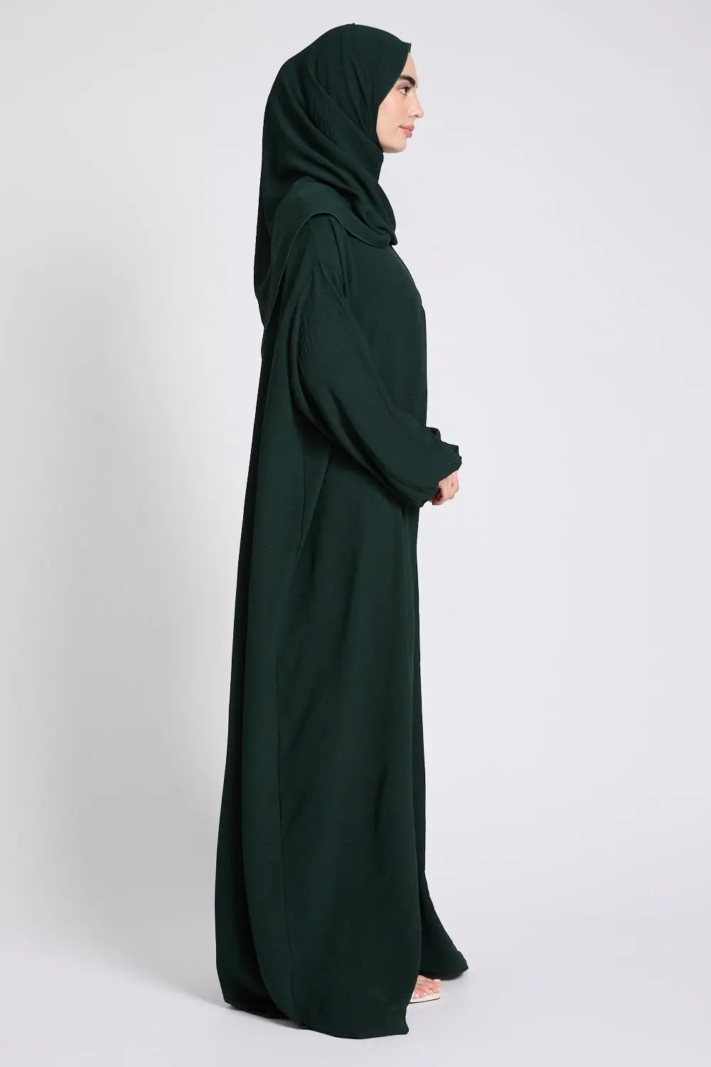 Person wearing a dark green abaya on a white background