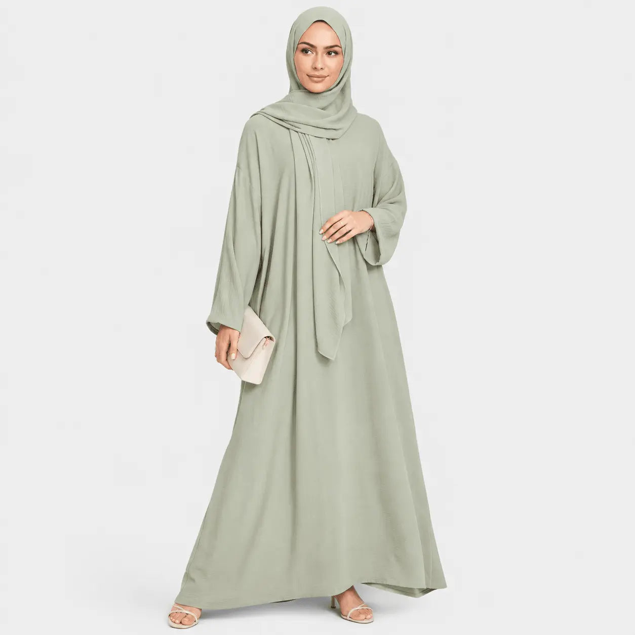 Woman wearing a light green abaya and hijab on a white background