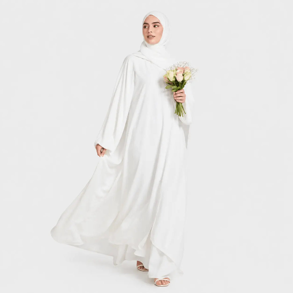 Woman in a white abaya holding flowers on a white background