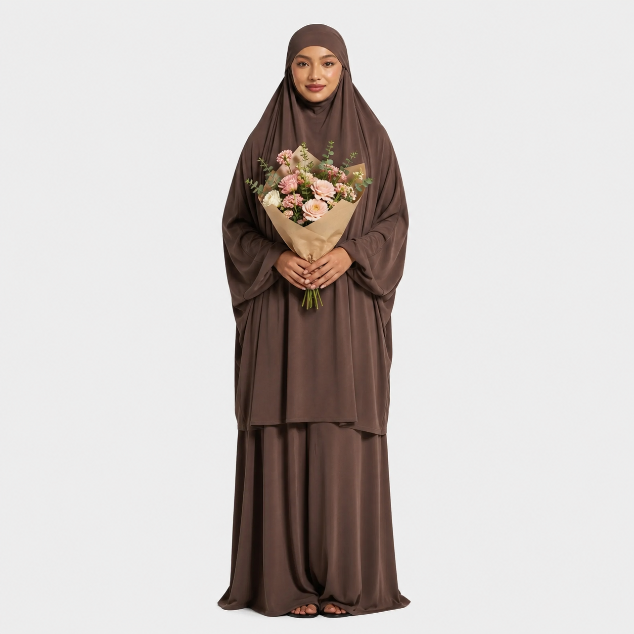 Woman in a brown abaya holding a bouquet of flowers on a white background