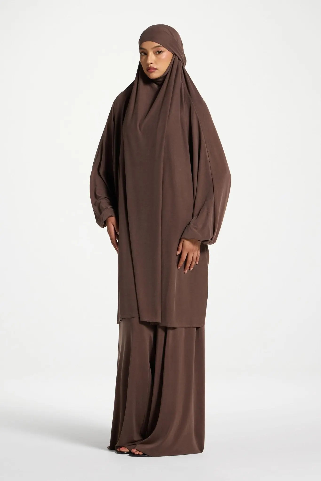 Woman wearing a brown abaya on a white background