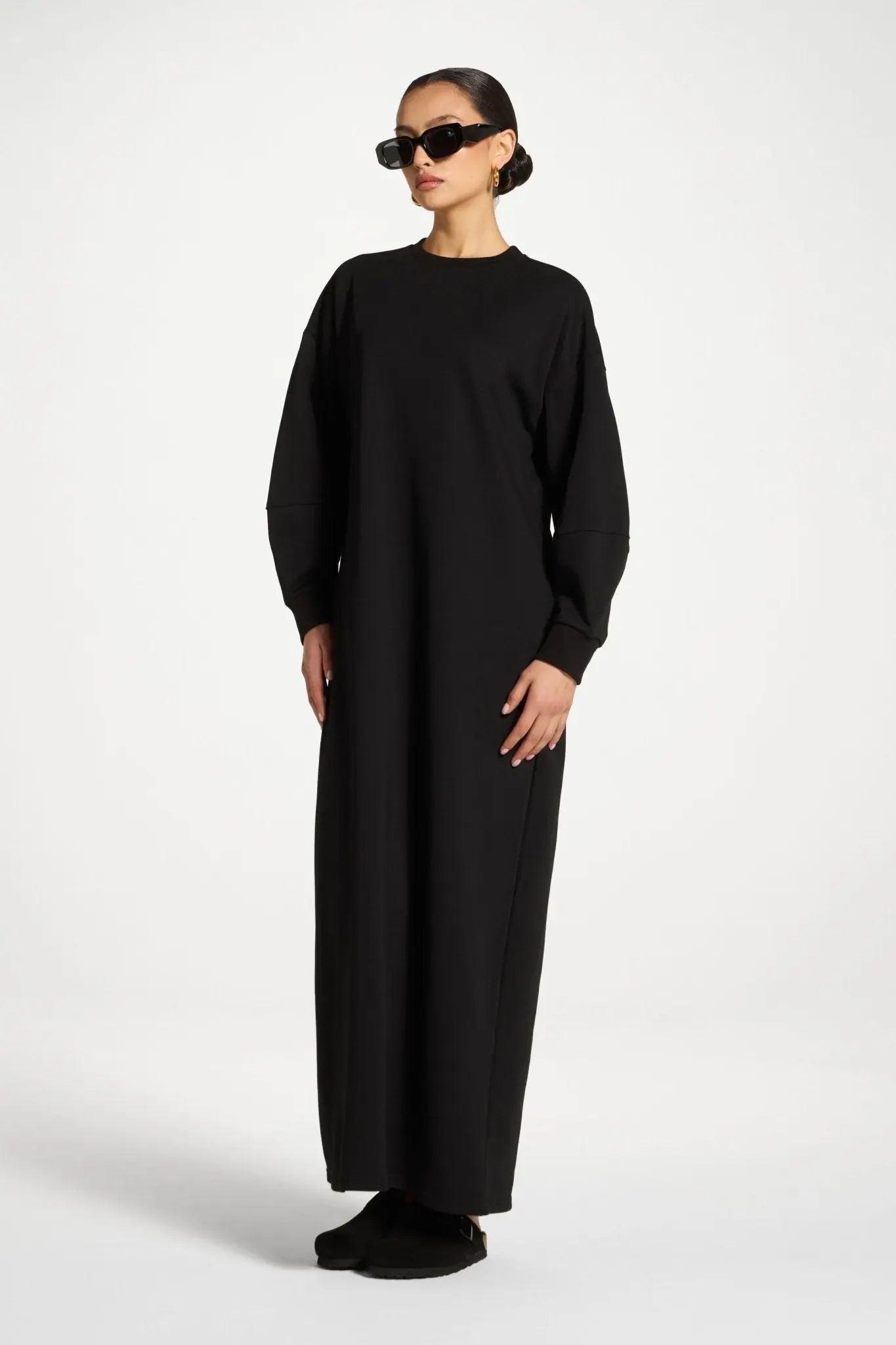 Person wearing a black long-sleeve dress on a white background