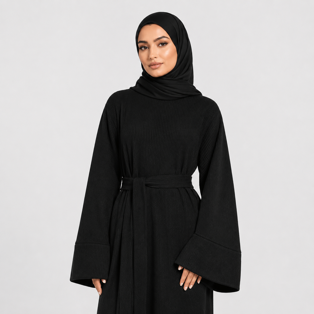 Woman wearing a black abaya and hijab on a light gray background