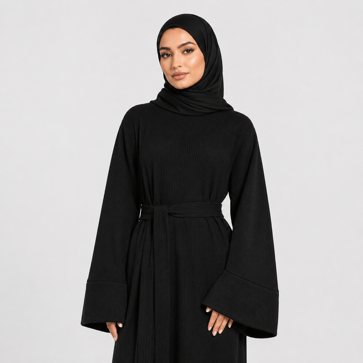 Woman wearing a black abaya and hijab on a light gray background