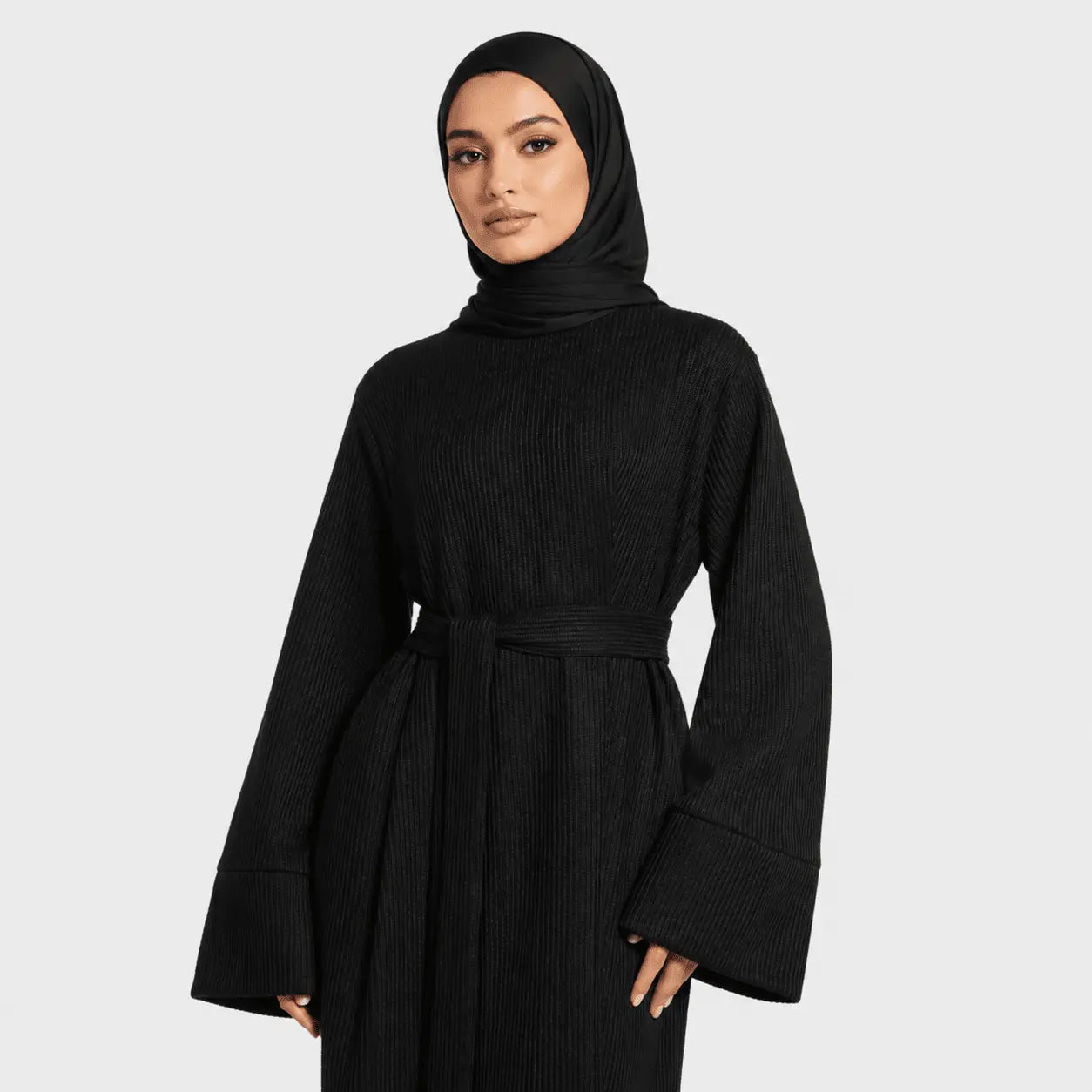 Woman wearing a black ribbed dress with a hood against a white background