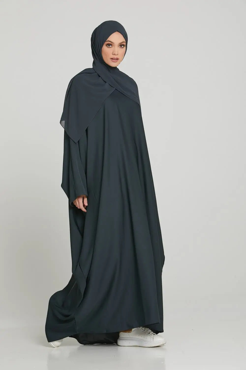 Woman wearing a dark gray abaya on a white background