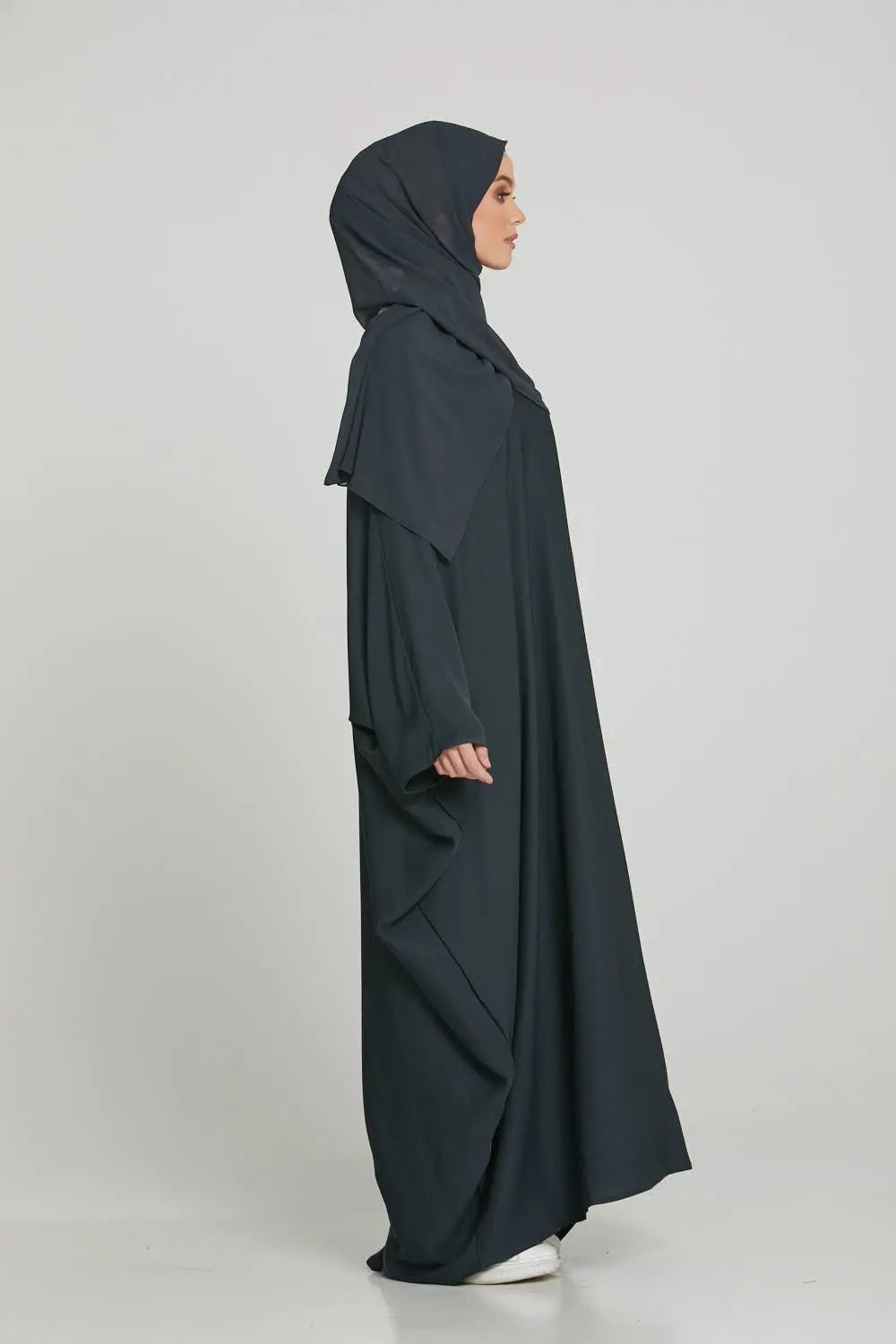 Woman wearing a black abaya on a white background