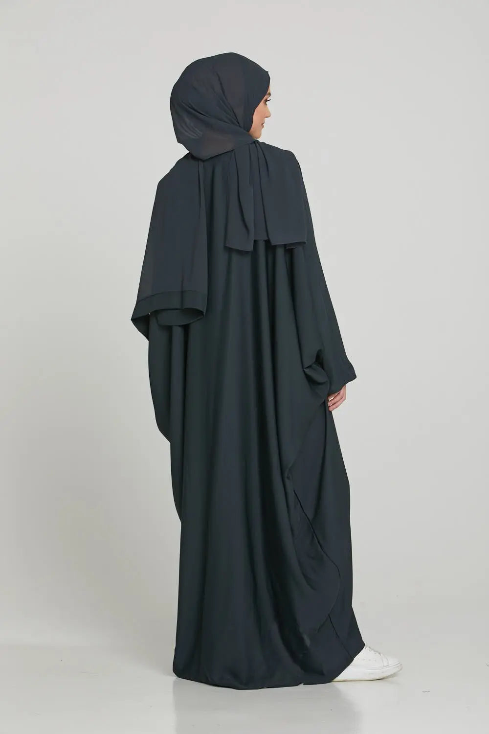 Person wearing a black abaya and hijab on a white background