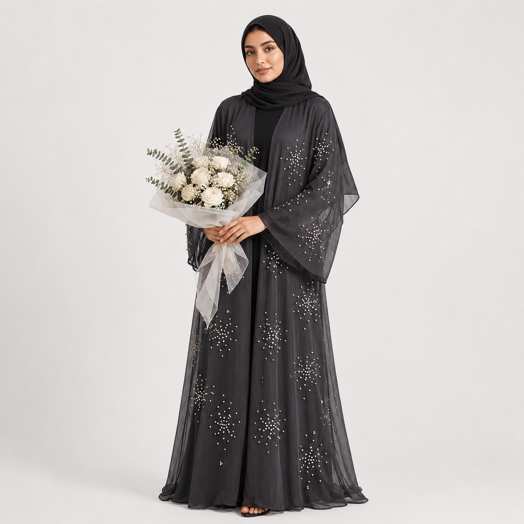 Woman wearing a dark gray abaya with star patterns, holding a bouquet of flowers on a white background