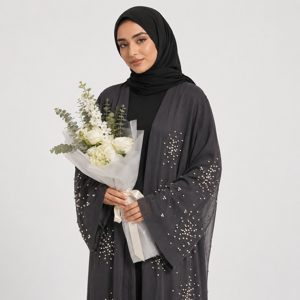 Woman wearing a black abaya with sequin details, holding a bouquet of flowers against a white background