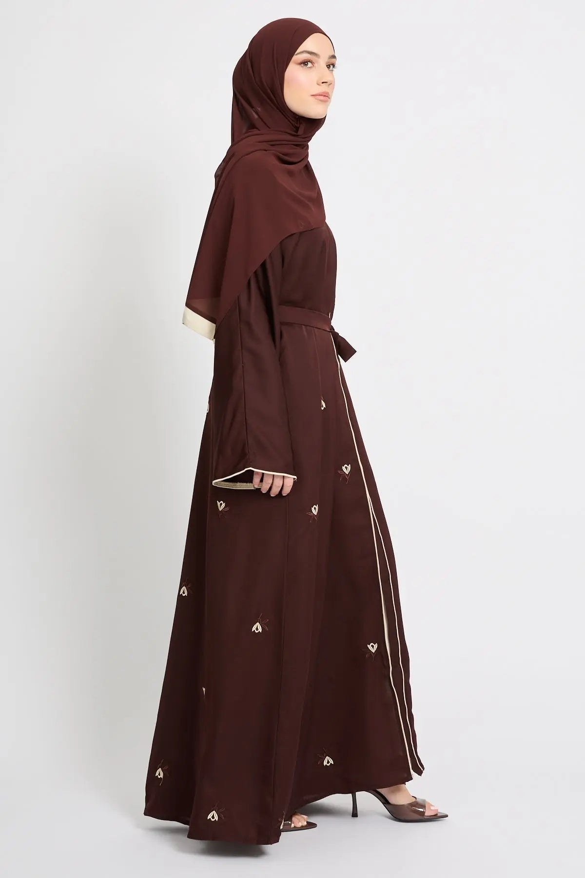 Woman wearing a brown dress with gold buttons on a white background